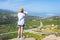 Woman in tourist clothes and straw hat with a map standing on top of a mountain. Concept