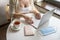 Woman tourist with cup of coffee putting medical protective face mask and passport at the table sitting near window in cafe in air