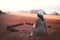 Woman tourist in dress sit on cliff at viewpoint on sunset in Wadi Rum desert - valley Wadi Saabit. Jordan explore concept