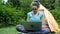 Woman tourist freelancer opens a laptop at a campsite and works in nature against the backdrop of a tourist tent.