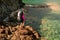 woman tourist with hiking gear stands on the rocky seashore with clear water