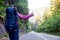 Woman tourist hitchhiking on empty mountain road surrounded by grassy rocky hills in Romania