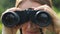 Woman tourist looking through binoculars closeup. Watch the object, spy.