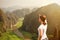 Woman tourist looking far away and enjoying valley and hills view from top of a mountain