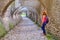 Woman tourist looking throw an archway with multiple arches, paved with cobblestone, in Biertan fortified church, Transylvania