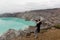 Woman tourist looks at the sulphur lake on the Ijen volcano on the island Java in Indonesia. Hiker female travel on top