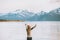 Woman tourist raised hands enjoying mountains and fjord view