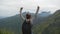 Woman tourist running to the edge of beautiful canyon, victoriously outstretching arms up. Young female hiker with