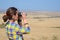 Woman tourist on safari in Africa, watching african savannah wildlife with binoculars