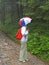 A woman tourist with an umbrella on her head will look into the woods on a rocky path. Tatra mountains, Poland