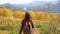 Woman tourist walking in fall forest on sunny autumn day. Hiker traveler woman hikking on mountain, enjoying panoramic