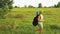 A woman tourist walks through a forest glade and looks through binoculars where to go next.