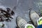 Woman in tourist waterproof hiking boots is standing in the water in a puddle