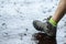 Woman in tourist waterproof hiking boots walking on water in puddles in the rain