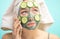 Woman with towel on head and face mask enriching with cucumbers via smartphone