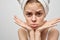 woman with a towel on her head on a light background and pimples on her face transitional age clean skin model