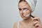 woman with a towel on her head magnifies pimple skin problems through a magnifier