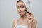 woman with a towel on her head magnifies pimple skin problems through a magnifier