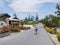 Woman with traditional hat walking in the street of Ngurbloat, a tiny colorful flowery village with a huge christian gotic style