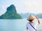 Woman with traditional looking at unique view of Halong Bay, Vietnam. Tourist traveling on cruise among Ha Long Bay rock pinnacles