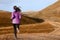 Woman trail runner running in mountain landscape. Female runner in warm clothes for autumn jogging cross country outdoors in