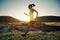 Woman trail runner running in sunset grassland