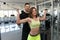 Woman Train Biceps On Machine With Personal Trainer