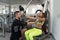 Woman Train Chest On Machine With Personal Trainer