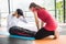 Woman trainer help sportsman sit ups in gym