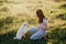 Woman training cute white puppy to behave in summer meadow in warm sunset light. Adorable fluffy puppy giving paw to girl owner.