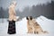 Woman trains Caucasian Shepherd and yard dog on a snowy ground in the park