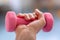 A woman  trains with pink dumb bells