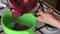 A woman transfers cranberries cooked with sugar from a saucepan into a colander. Prepares mashed potatoes for marshmallow.