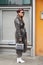 Woman with transparent gray raincoat and white boots before Giorgio Armani fashion show, Milan Fashion Week