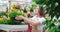 Woman transplants beautiful flower pots in greenhouse.