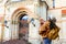 Woman traveler with backpack holding dog examines architectural monument .