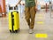 Woman traveler in casual clothes with backpack carrying yellow suitcase at the check-in desk at the airport terminal tourism