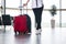 woman traveler climbs the stairs in airport or train station lounge; legs and suitcase close-up