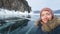 Woman traveler makes a selfie against the rock and Baikal ice. Smiling traveler in winter clothes