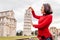 Woman traveler making funny poses in front of the famous leaning tower in Pisa, Italy. Happy travel photos in Italy concept