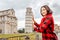 woman traveler making funny poses in front of the famous leaning tower in Pisa, Italy. Happy travel photos in Italy concept