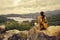 Woman traveler sits and looks at the edge of the cliff on the sea bay