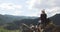 Woman traveler sits on top of mountain admires nature view with river in valley.