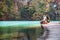 Woman traveler sits on wood bridge on mountain lake at sunny autumn day