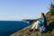 Woman traveler sitting on top of a cliff on seaside