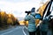 Woman traveler taking a photo on mountain with car on roadtrip, autumn vacation.