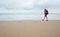 Woman traveler walk on empty ocean beach in rainy day