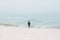 Woman traveler walking alone on foggy ocean beach