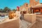 Woman traveler wearing dress and turban walking through the streets of an old Arab town or village in the middle of the