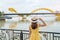 Woman Traveler with yellow dress visiting in Da Nang. Tourist sightseeing the river view with Dragon bridge at love lock bridge.